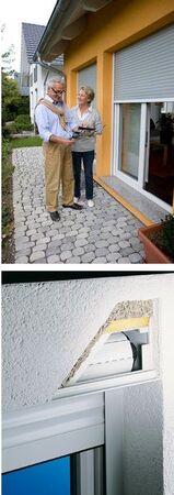 Älteres Paar bespricht vor Haus mit Rollladen die energetische Sanierung und Dämmung.