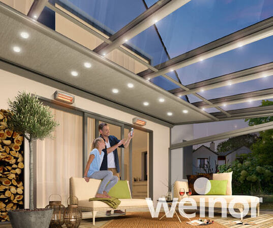 Modernes Terrassendach mit LED-Beleuchtung und Heizstrahlern, Paar genießt Abend.